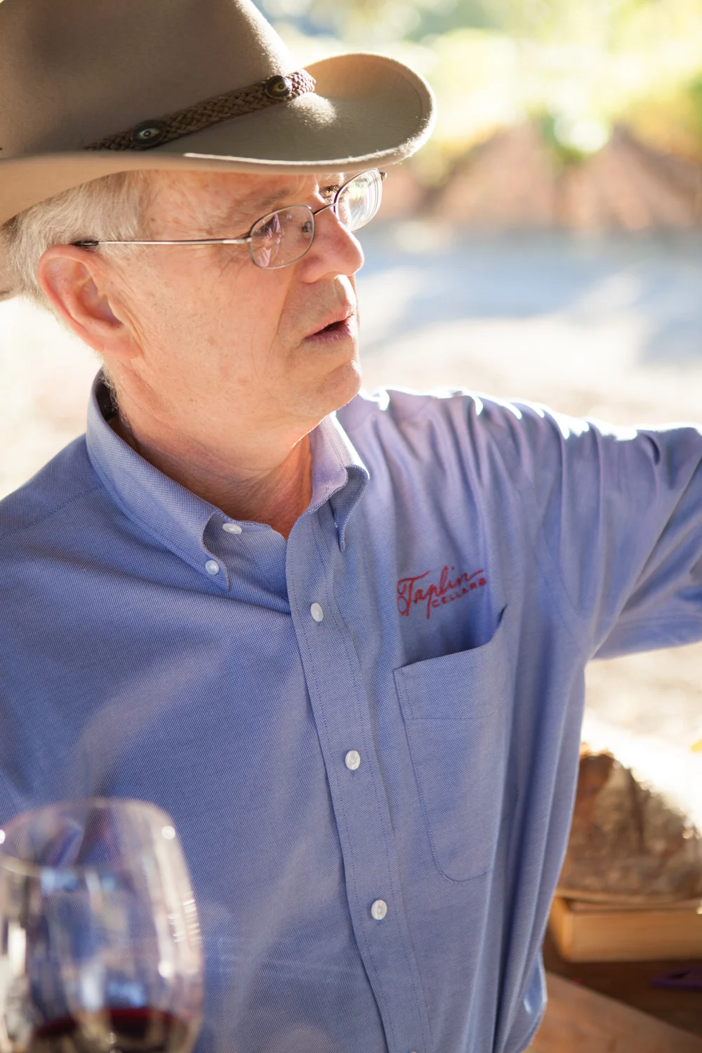 Stephen Taplin in a wide-brimmed hat and blue Taplin Cellars shirt in the vineyard